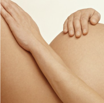 Focus d'image sur le ventre de femme enceinte d'une femme allongée avec la main posée sur le ventre