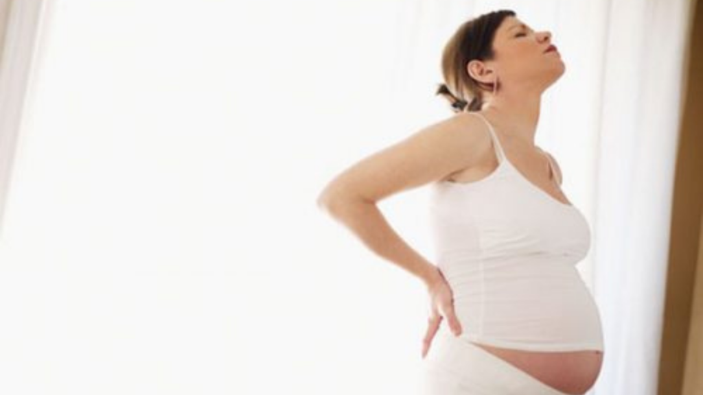 femme enceinte se tenant le dos et souffrant de douleur et maux